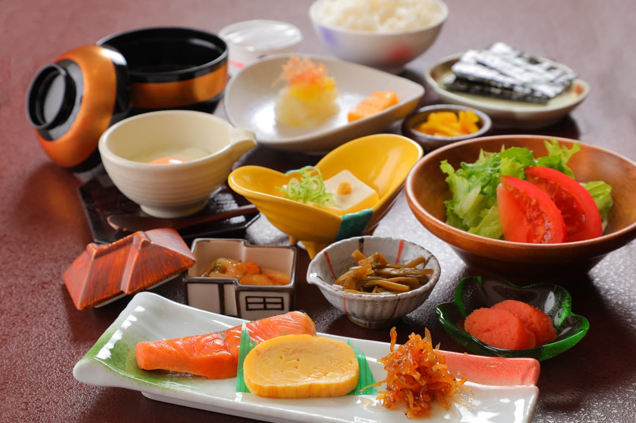 Traditional Japanese breakfast set with grilled salmon, rolled egg, salad and small dishes at Mori no Yu Sanseikan