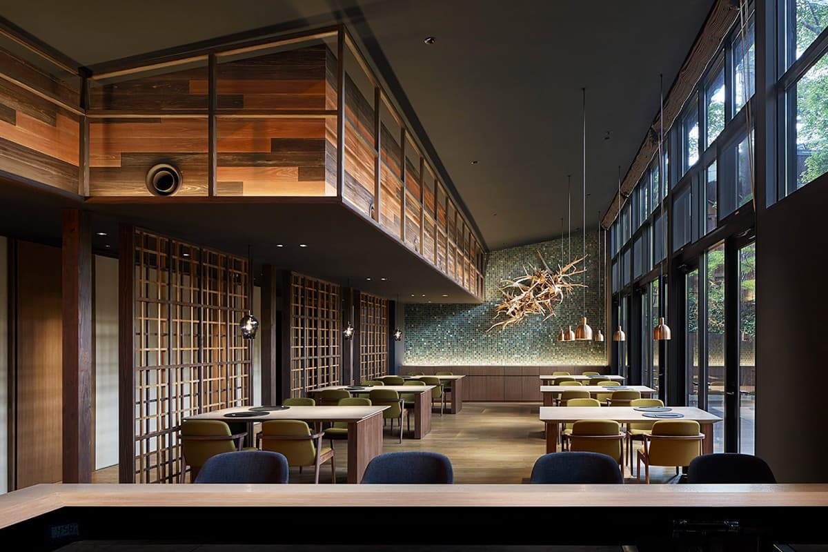 Bright high-ceilinged dining hall with wooden tables, lattice screens and tiled accent wall