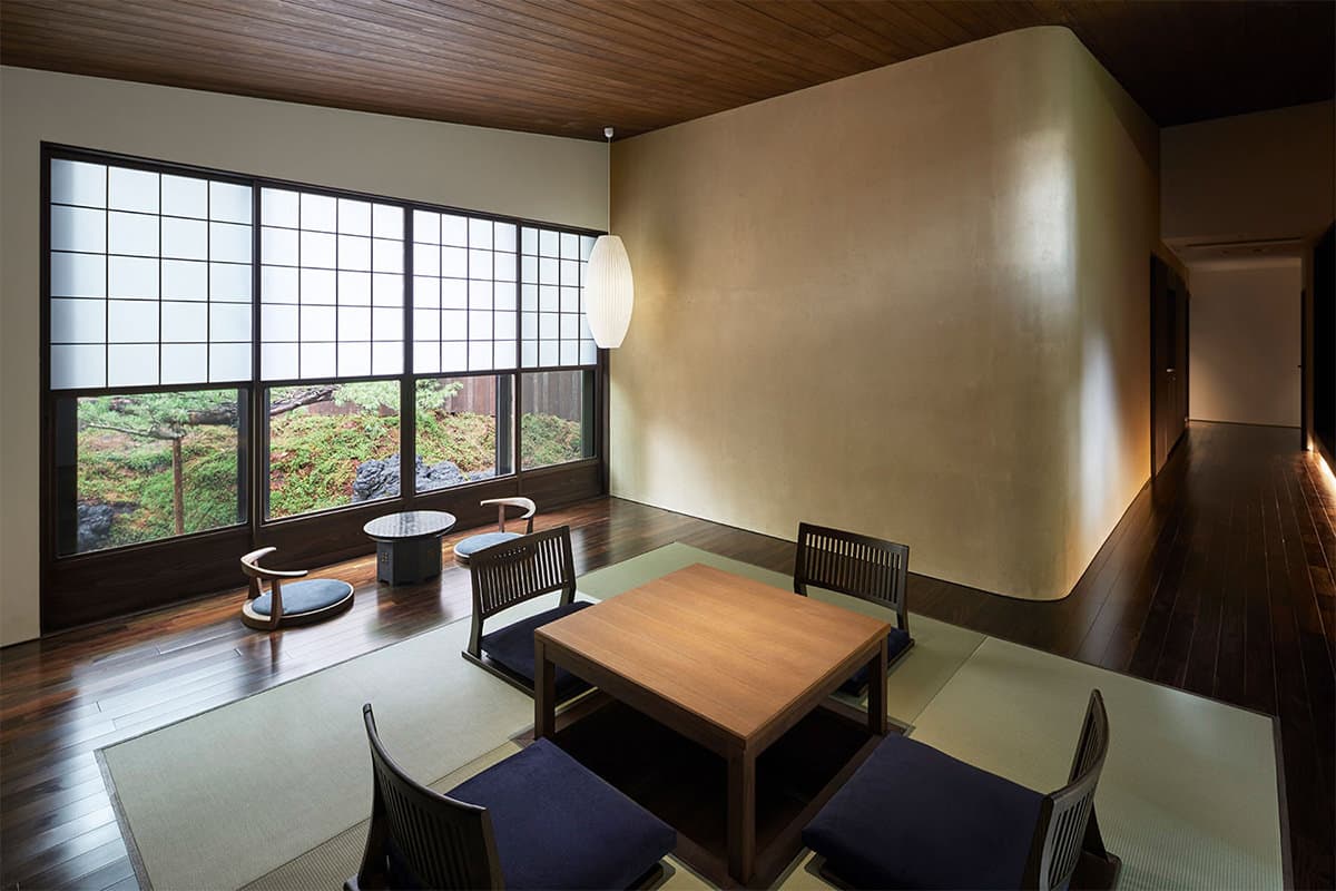 Minimalist tatami room with low wooden table and shoji windows overlooking a moss garden