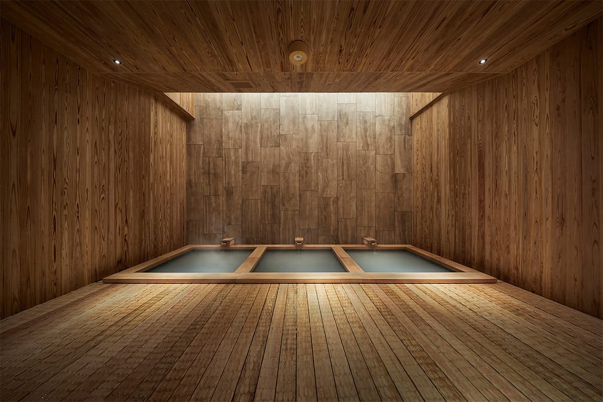 Cedar-clad indoor onsen bath with three connected wooden soaking pools