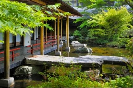 Japanese garden with a pond, stone bridge and open corridor