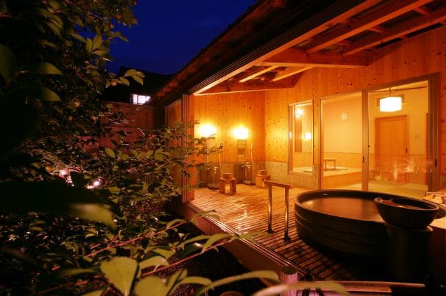 Private open-air bath on a guest room terrace lit at dusk