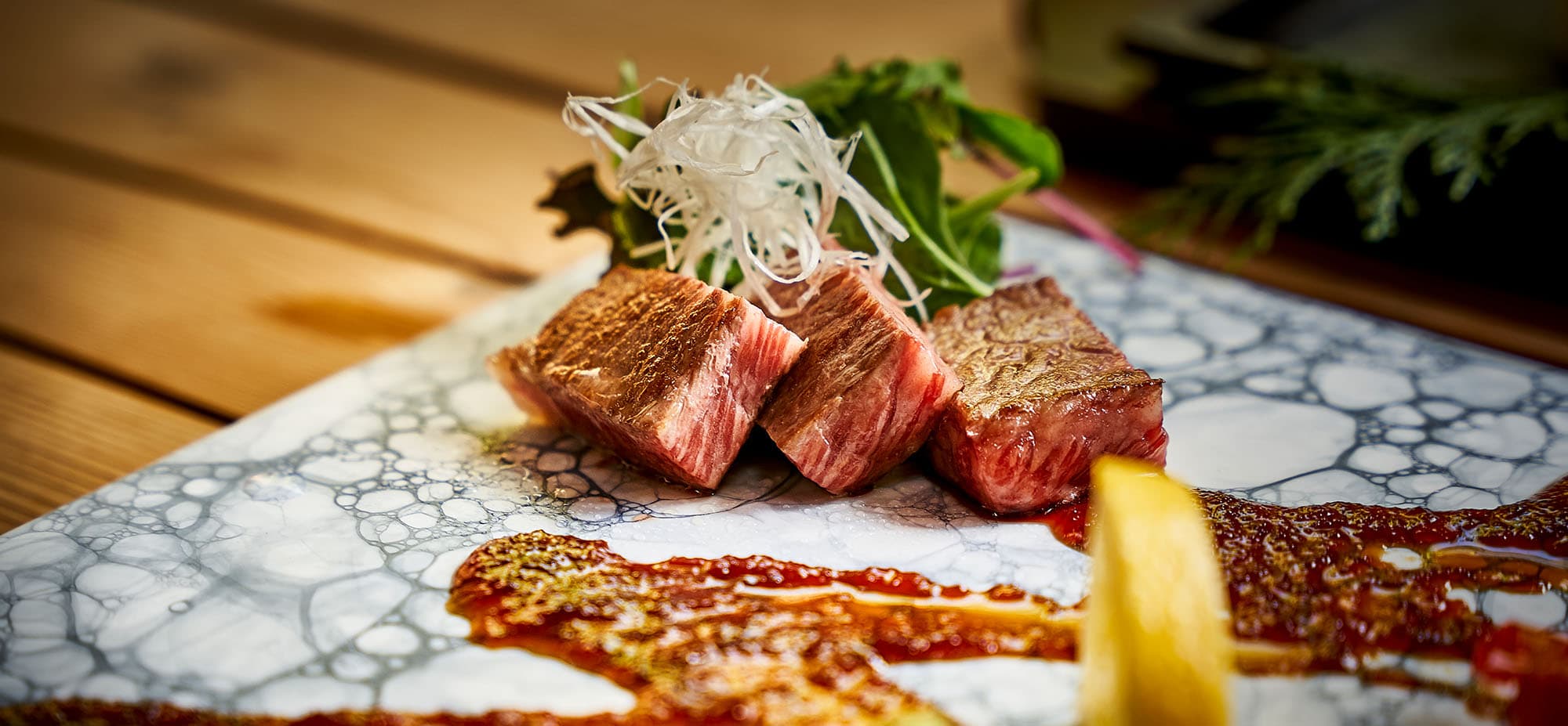 Seared local wagyu beef steak with asparagus and shredded leek on a marbled plate at Koto no Niwa