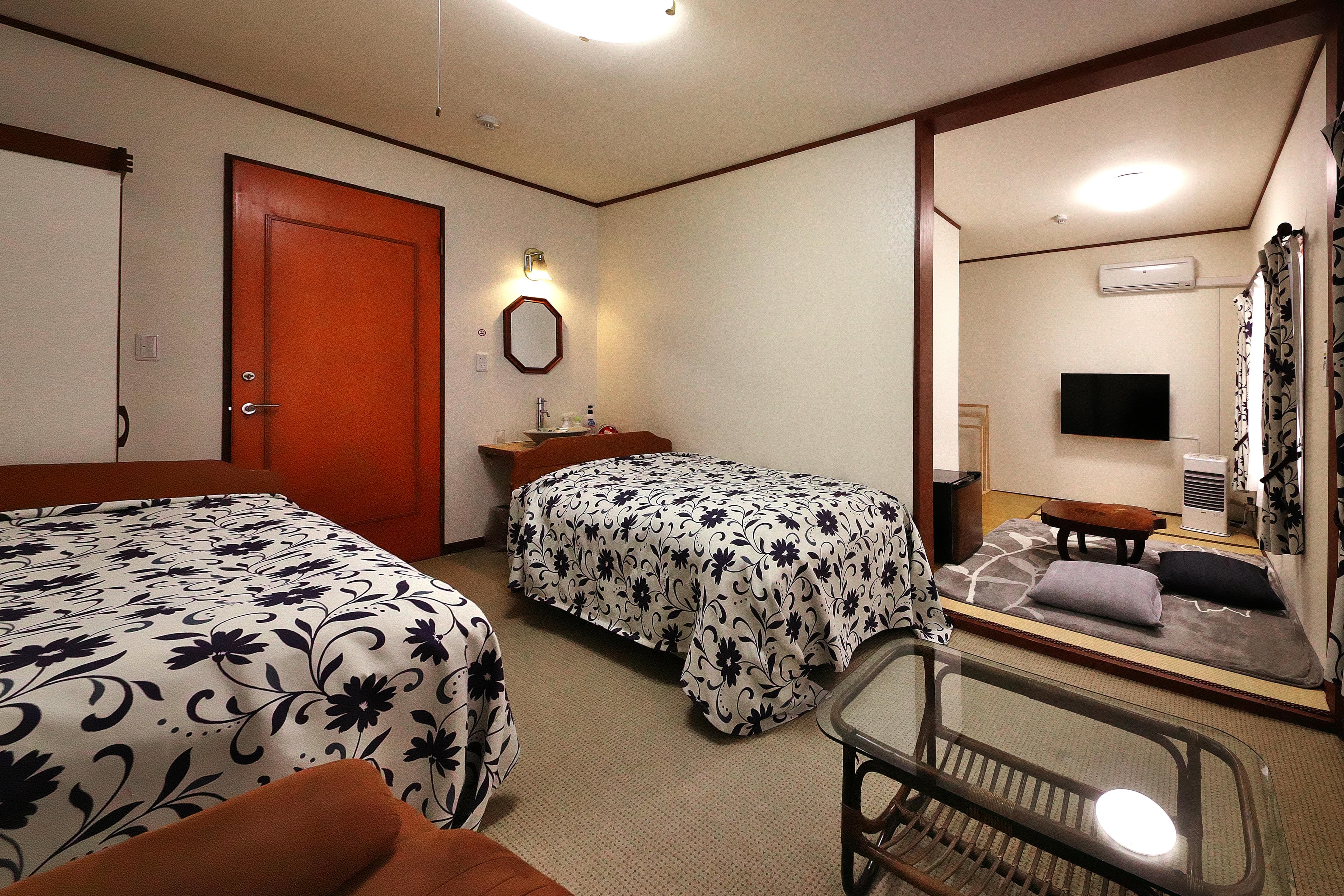 Western-style guest room with two beds, a wash counter and an adjoining tatami sitting area