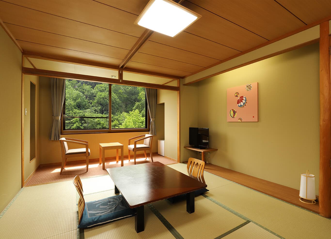 Traditional tatami guest room with low table, floor chairs and a forest view at Park Hotel Miyabitei in Noboribetsu Onsen