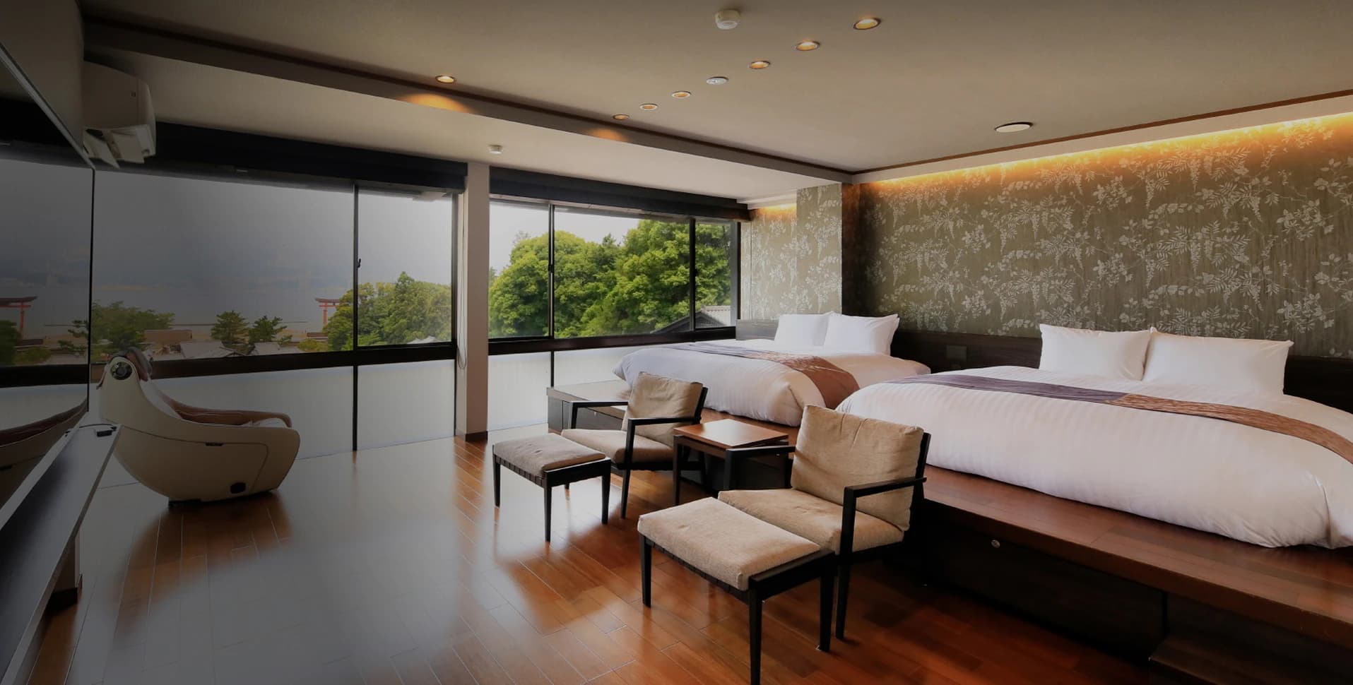 Spacious seaside guest room at Hotel Kikunoya with twin beds, lounge chairs and large windows facing Miyajima's Seto Inland Sea