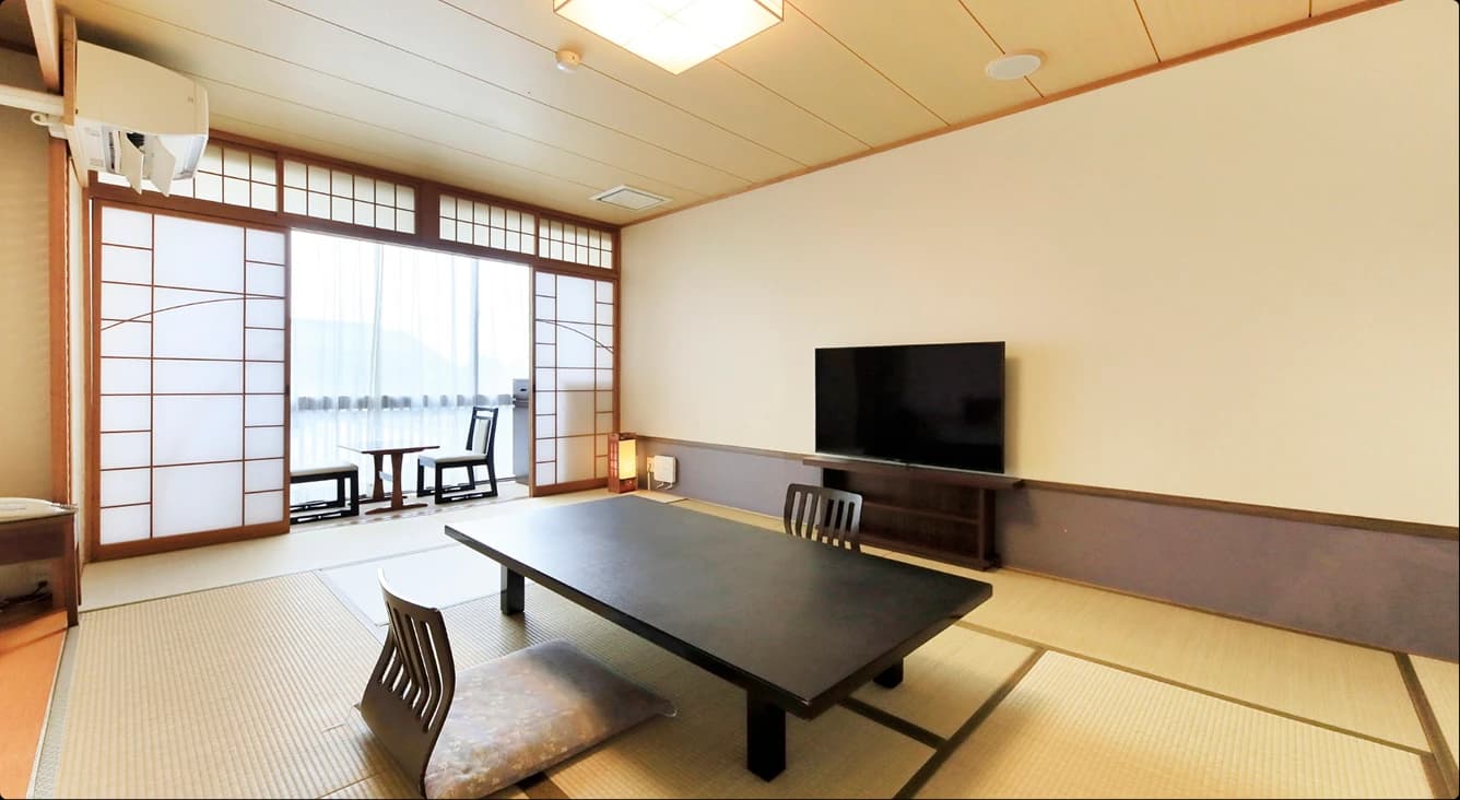 Japanese-style tatami room at Hotel Kikunoya with a low table, floor cushions and sea-facing windows on Miyajima island