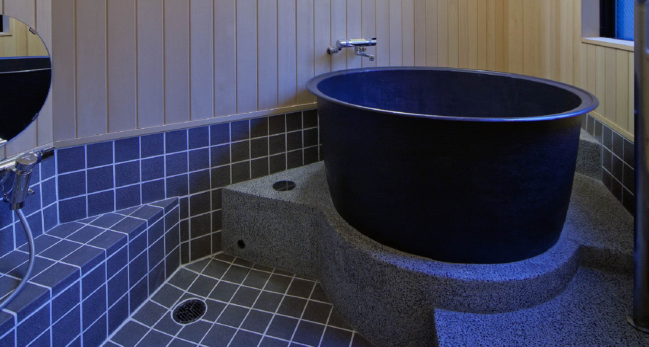 Single round black ceramic soaking tub on stone base in a private bath at Mizuhaso