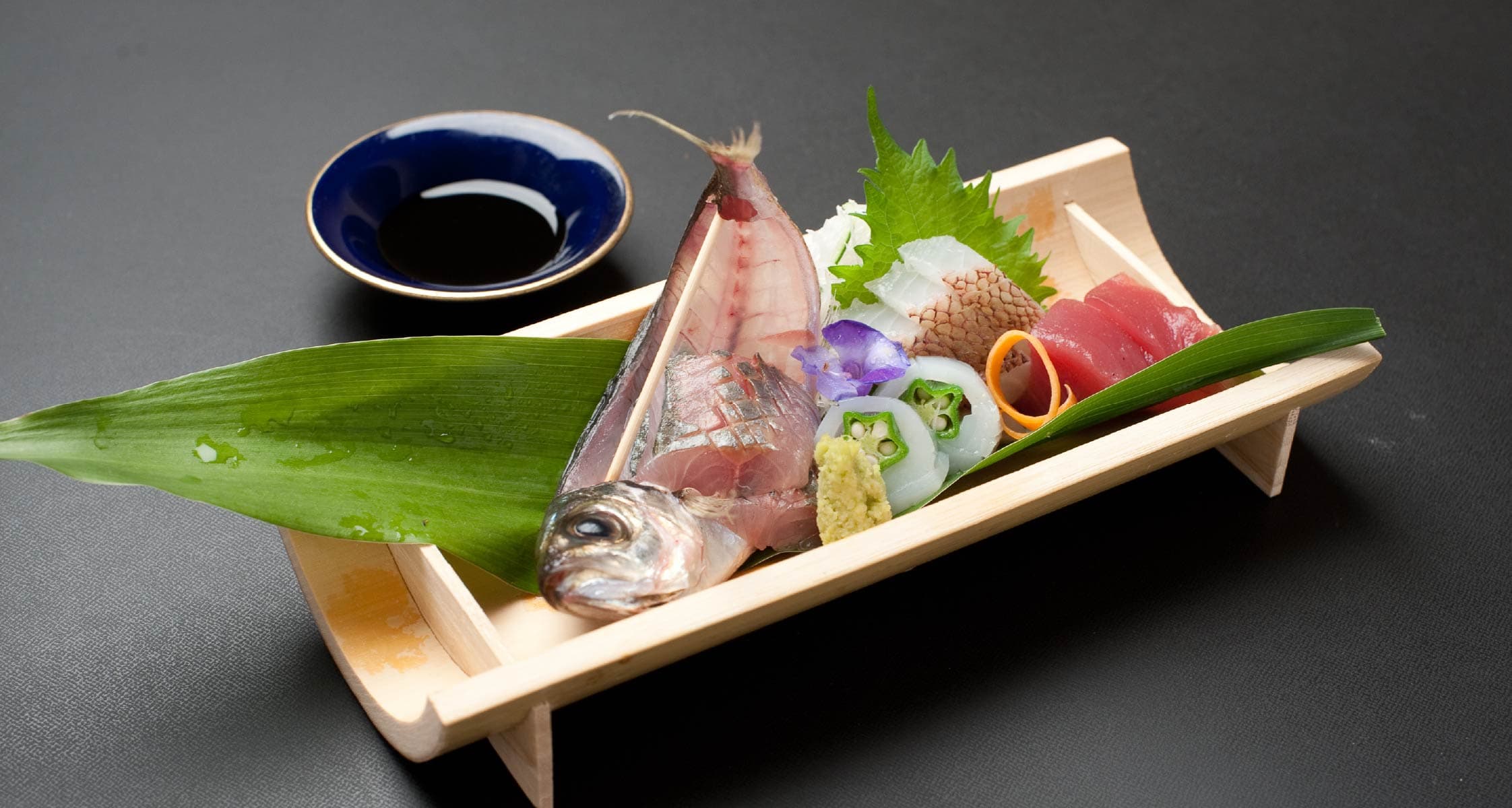 Fresh sashimi platter on a wooden boat tray with shiso and wasabi at Mizuhaso