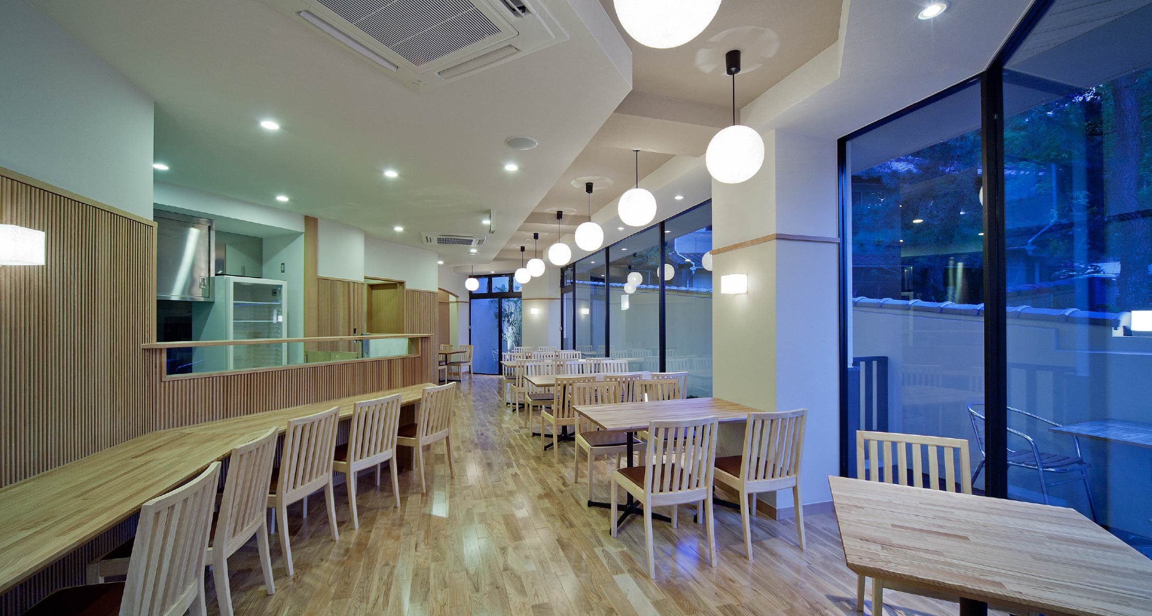 Light-wood dining room at Mizuhaso with pendant lamps and large windows onto greenery