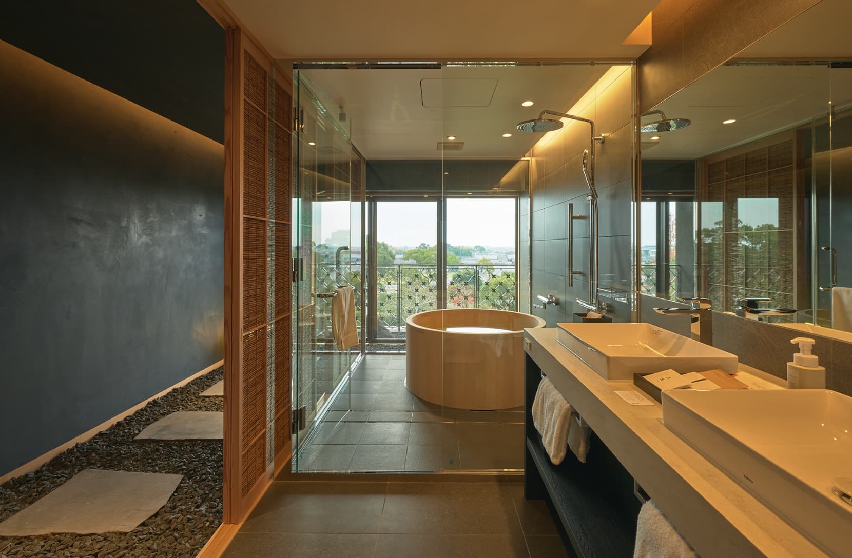 Private in-room hinoki cypress soaking bath set in dark slate tiling with a wooden stool and bucket at Ohana