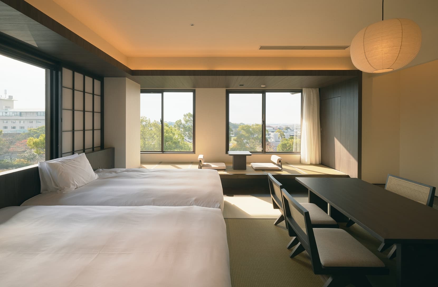 Bright Ohana bedroom with a wide window looking out over the historic pond garden and the inn's traditional tiled-roof buildings