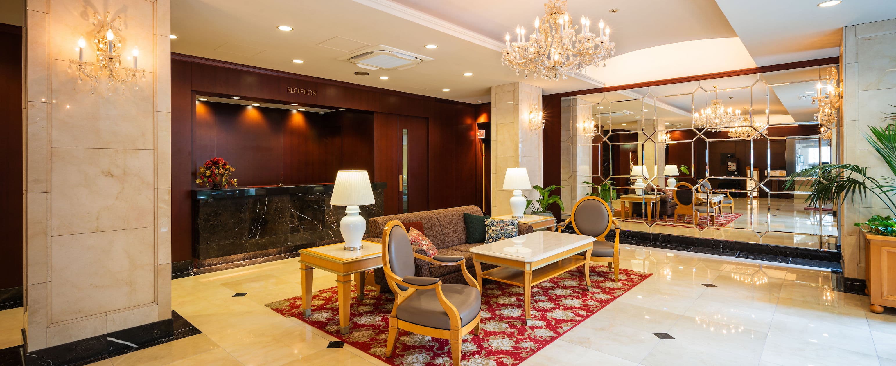 Elegant lobby lounge at Hotel Patio Dogo with chandelier, marble floor and reception desk