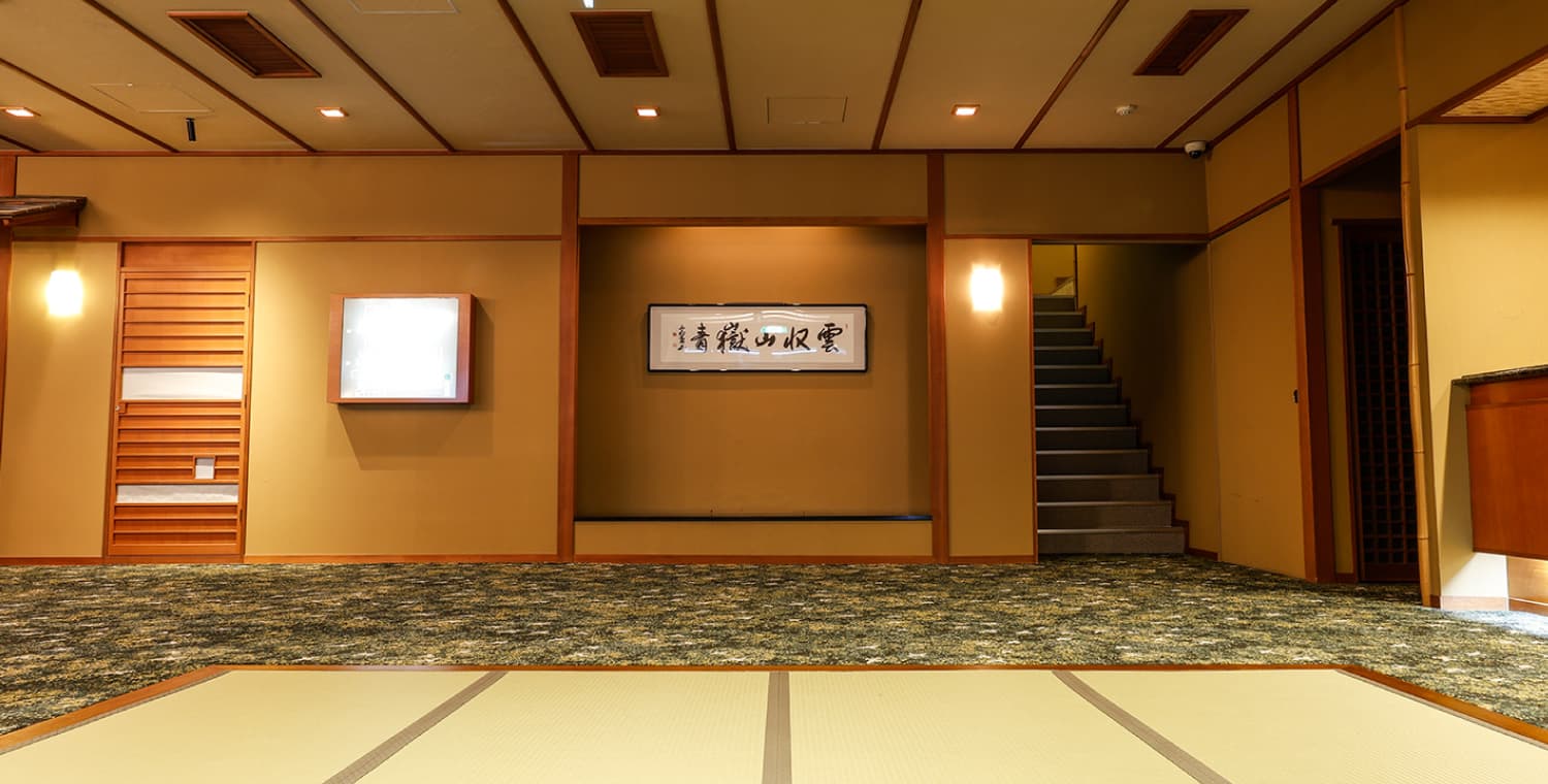 Lobby and tatami common area at Ryokufukaku with calligraphy scroll and staircase