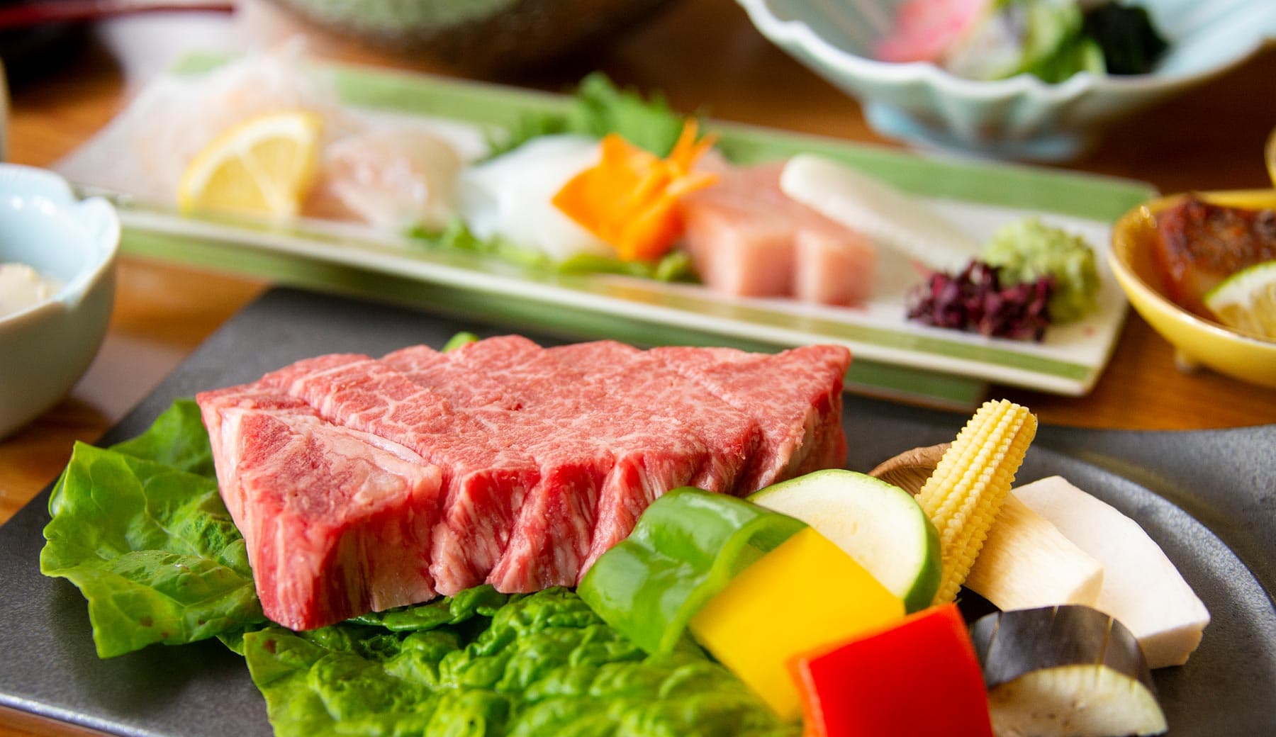 Premium marbled Kobe beef steak over lettuce with a seasonal sashimi platter plated for a kaiseki dinner at Motoyu Ryusenkaku, Arima Onsen