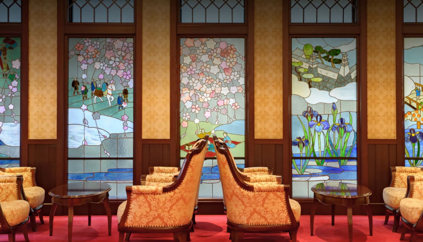 Stained-glass windows and gold upholstered armchairs in the heritage lounge at Kanazawa Hakuchoro Hotel Sanraku