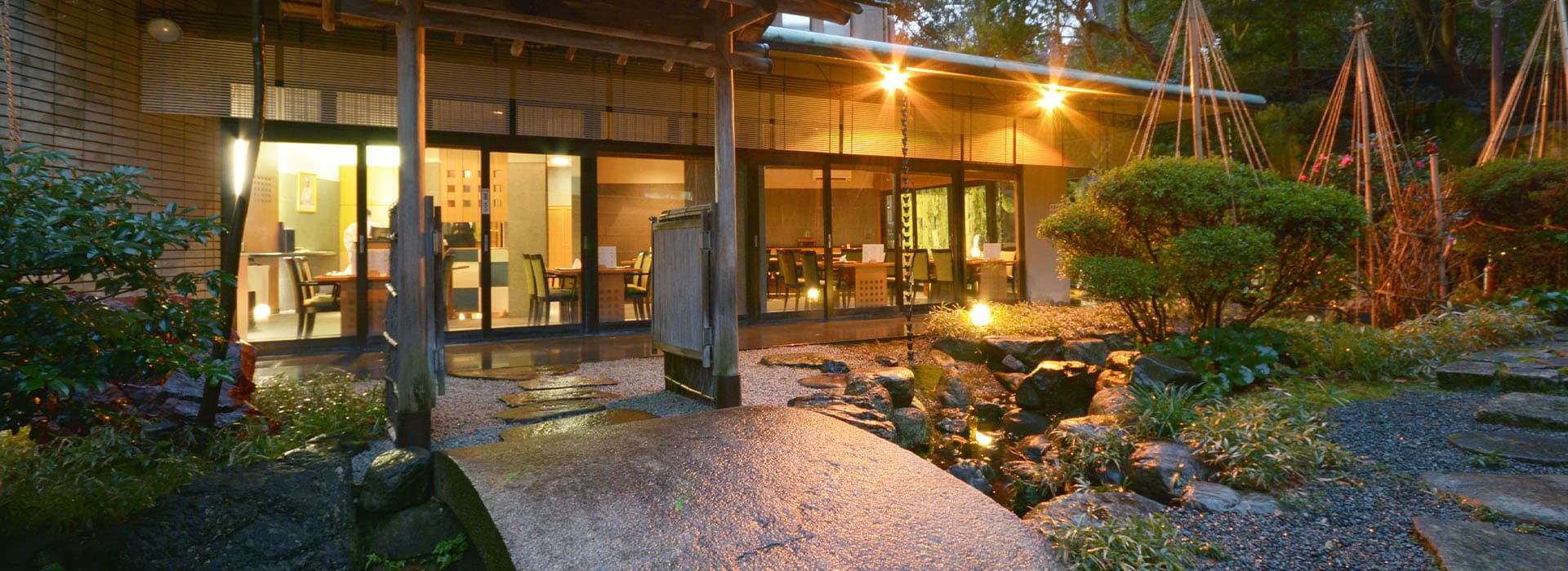 Lantern-lit garden and dining room exterior at dusk at Kanazawa Hakuchoro Hotel Sanraku