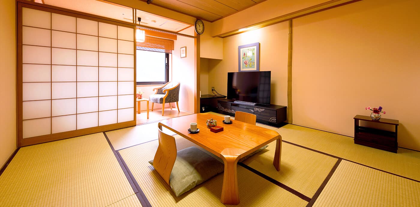 Japanese-style tatami guest room with low table and shoji screens at Kanazawa Hakuchoro Hotel Sanraku