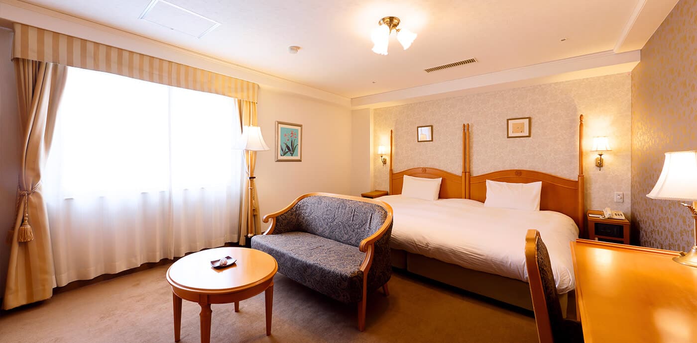 Bright Western-style king room with sofa and classic wood furnishings at Kanazawa Hakuchoro Hotel Sanraku