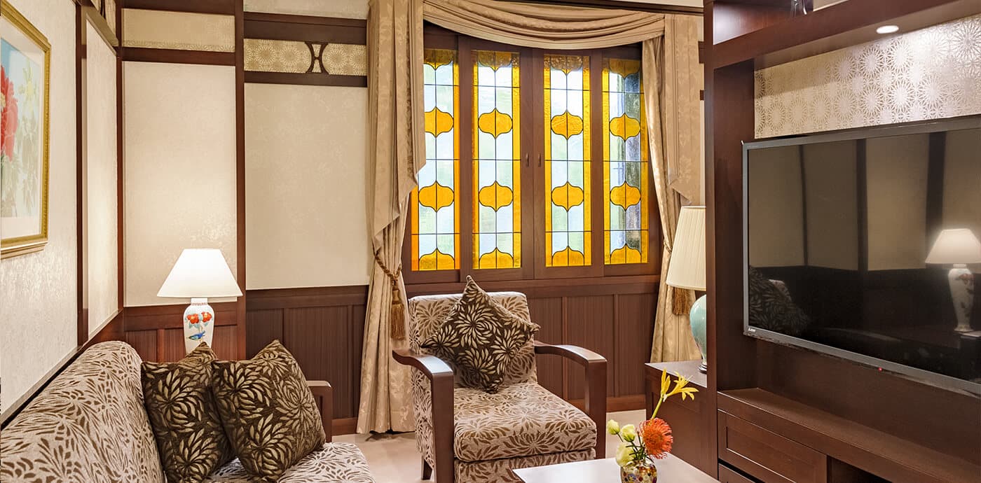 Spacious luxury suite with sofa, twin bed and stained-glass bay window at Kanazawa Hakuchoro Hotel Sanraku
