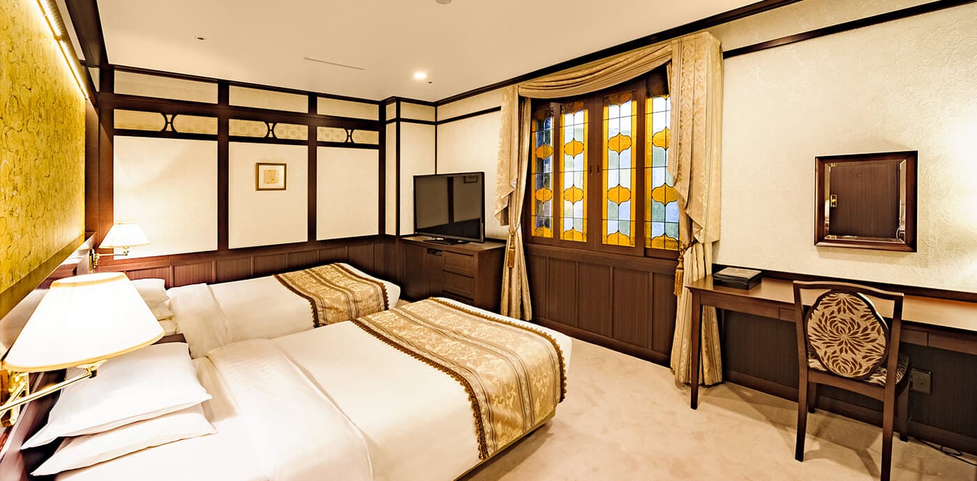 Romantic twin room with brocade bed runners and stained-glass window at Kanazawa Hakuchoro Hotel Sanraku