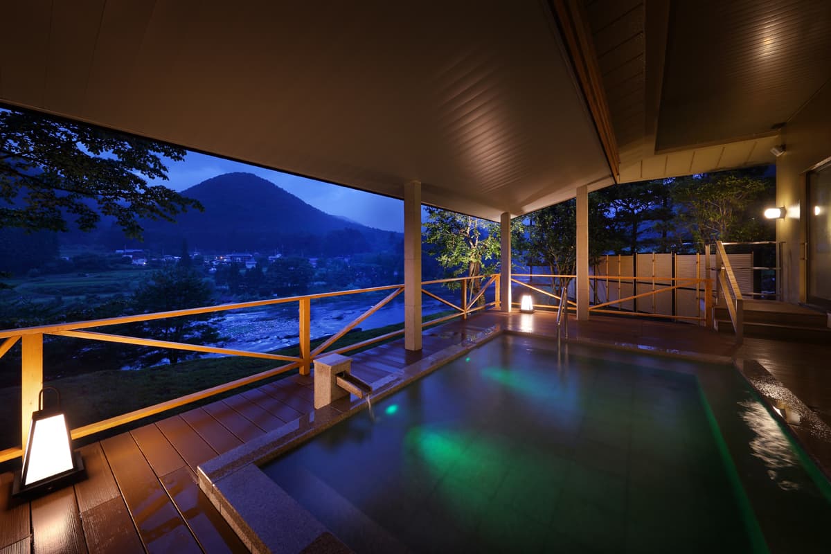 Open-air bath at dusk overlooking the wooded gorge
