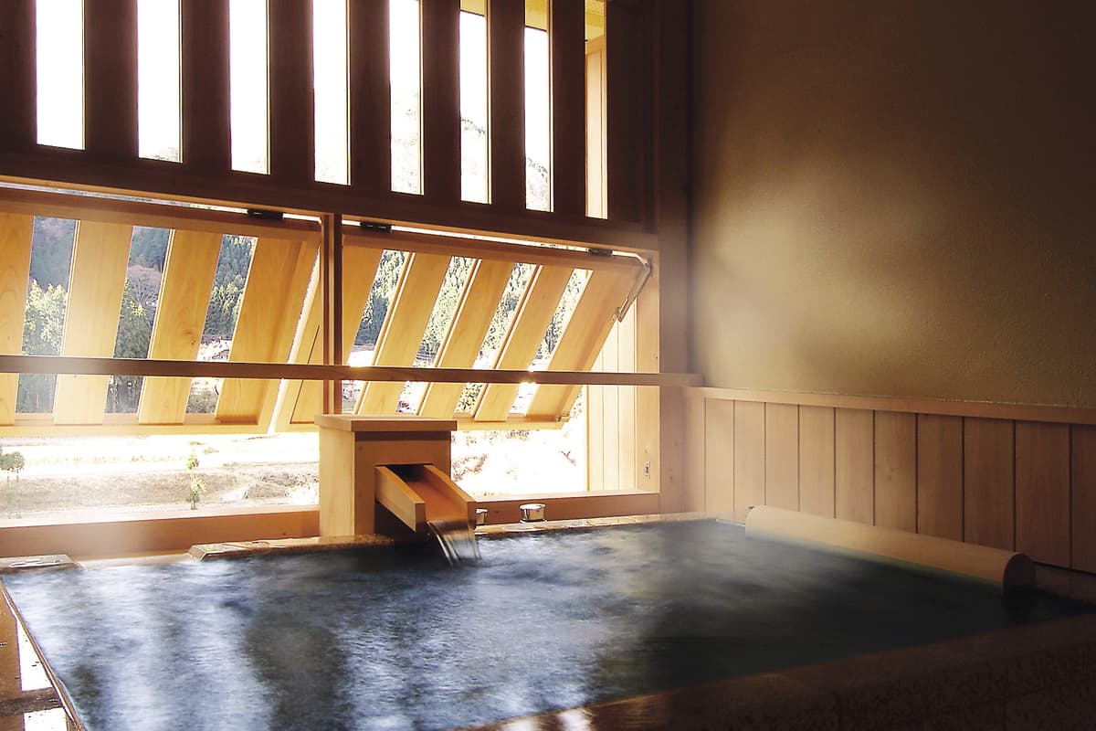 Stone bath with slatted light streaming through wooden screens