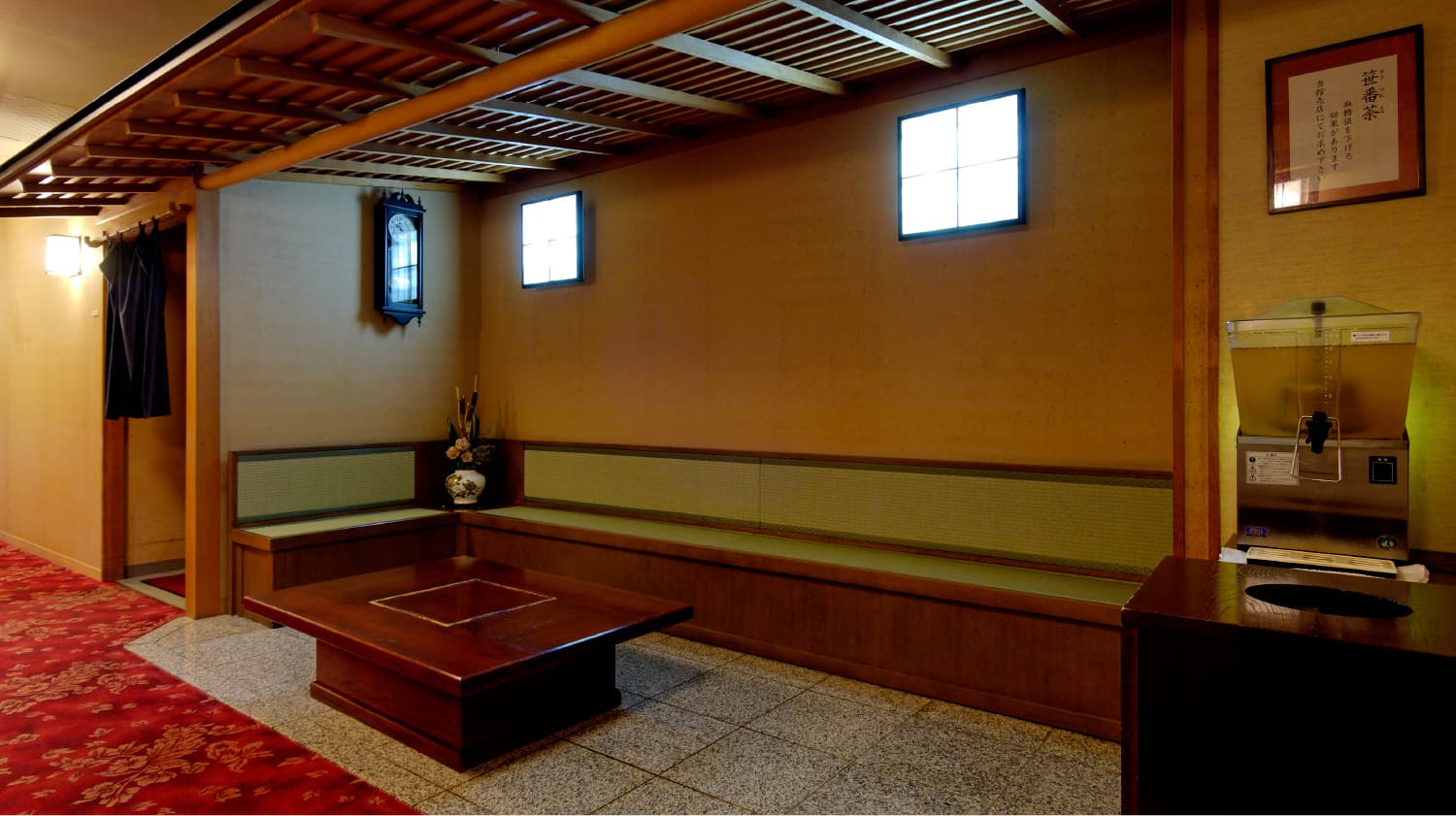 Quiet bath-house lounge with tatami bench, low wooden table and tea dispenser at Shirafuneso Shintaku Ryokan, Shirahone Onsen