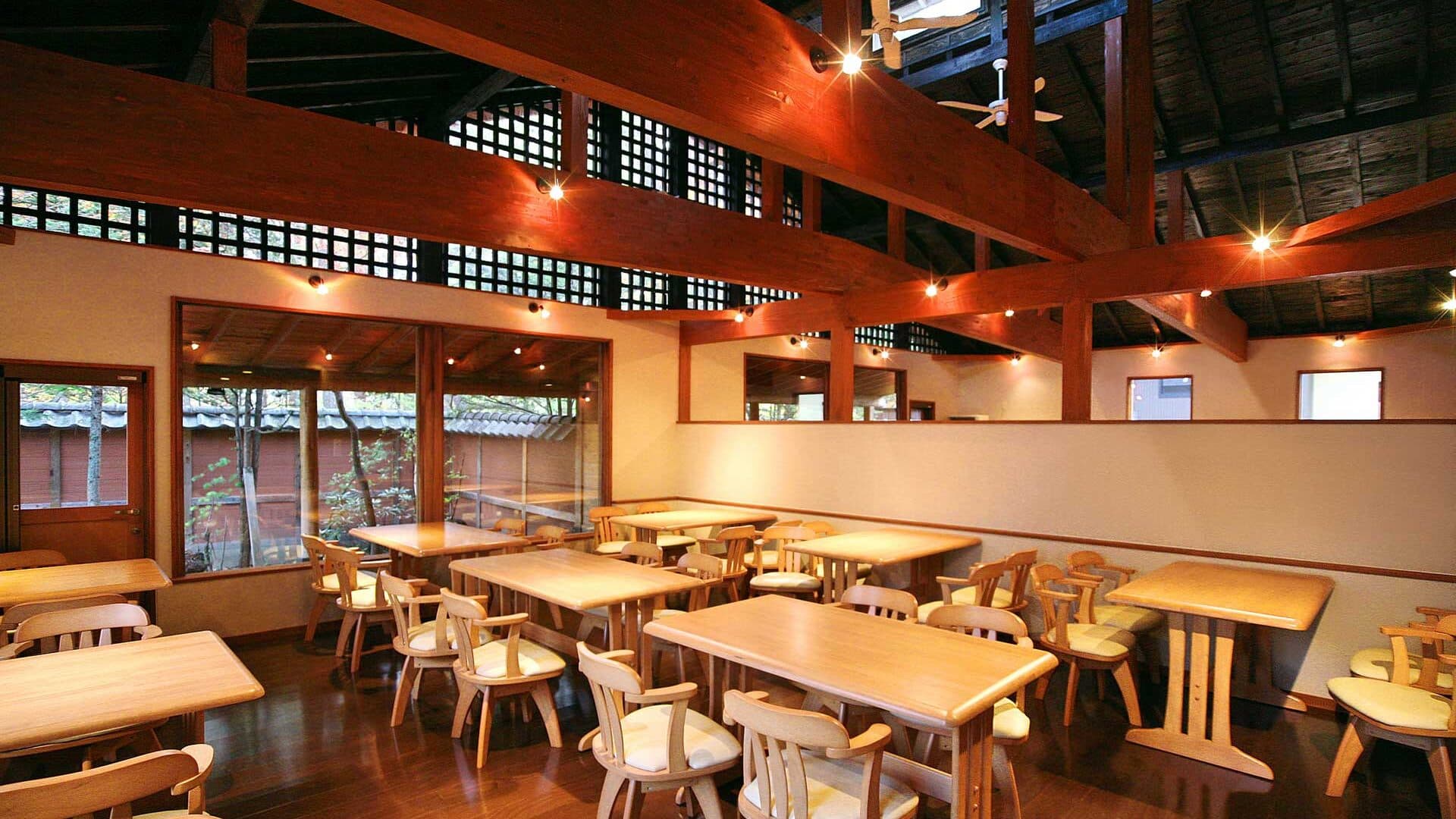 Wood-beamed dining hall at Kusatsu Skyland Hotel with light timber tables and chairs and high clerestory windows