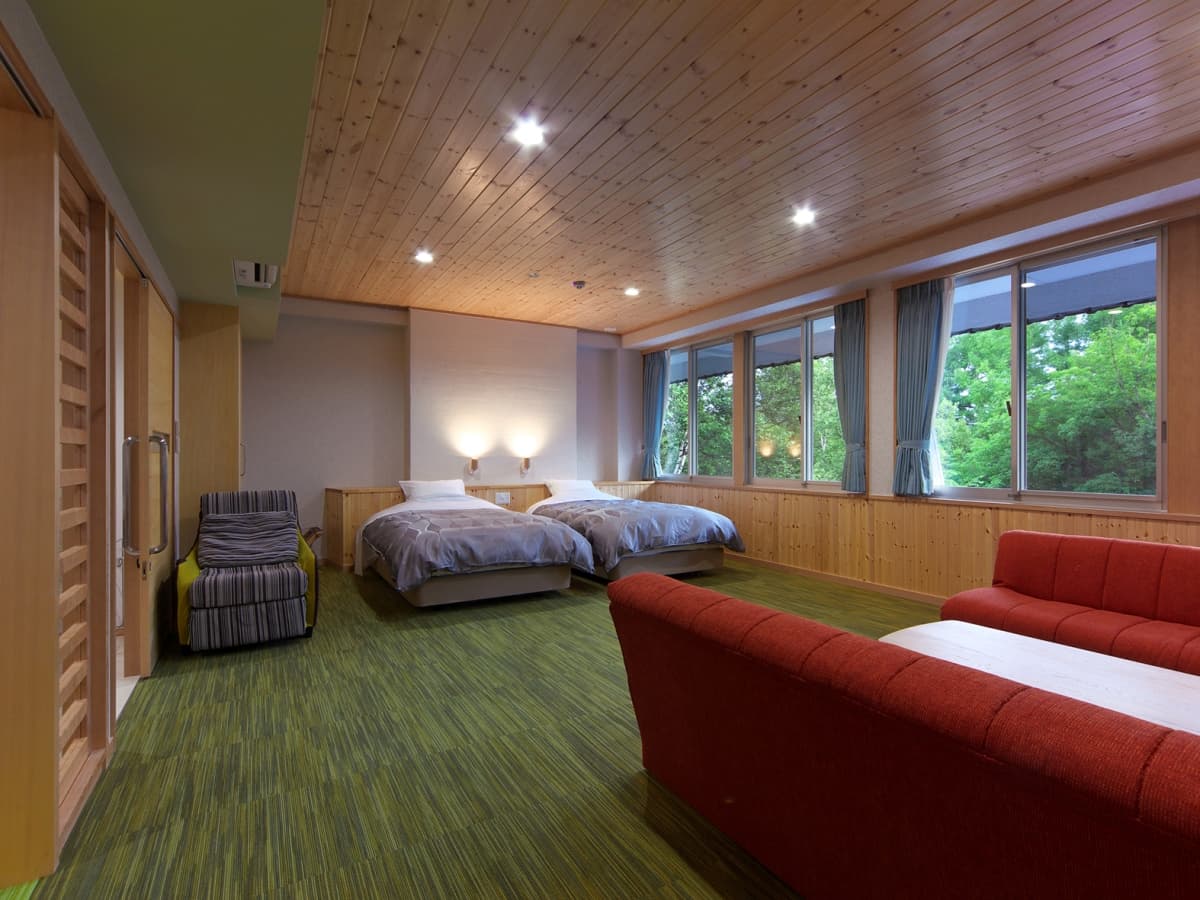Japanese-Western twin guest room at Kusatsu Skyland Hotel with wood paneling, green carpeting and forest-view windows
