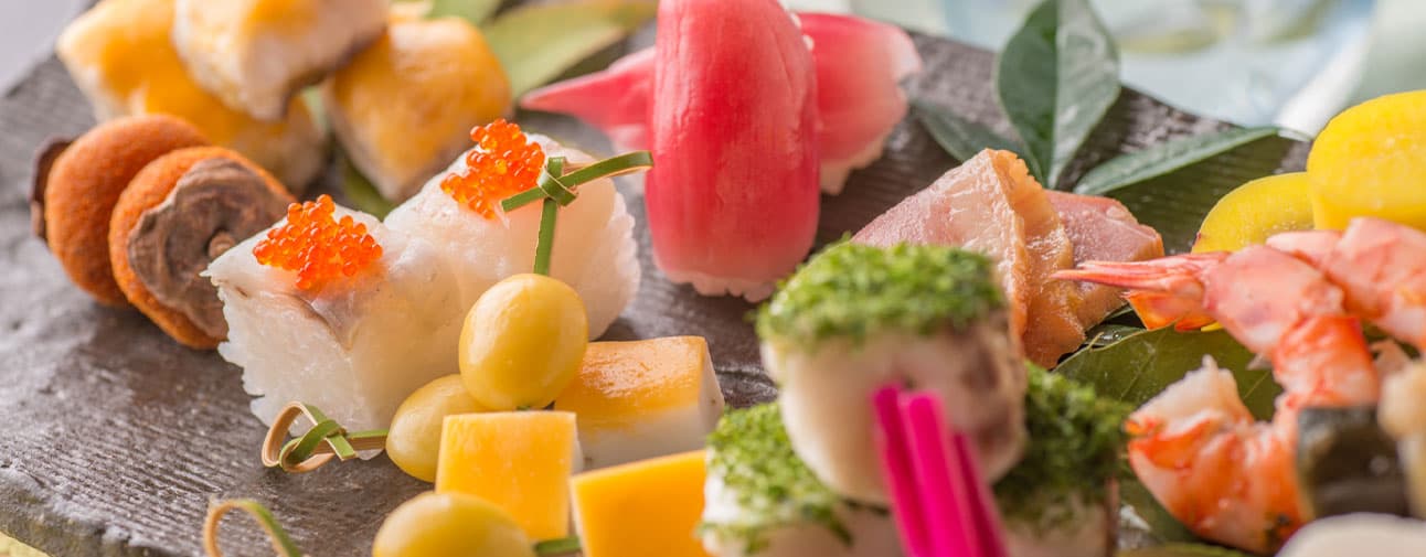 Close-up of assorted Hida nigiri sushi and seasonal small bites plated on slate at Honjin Hiranoya Kofukan