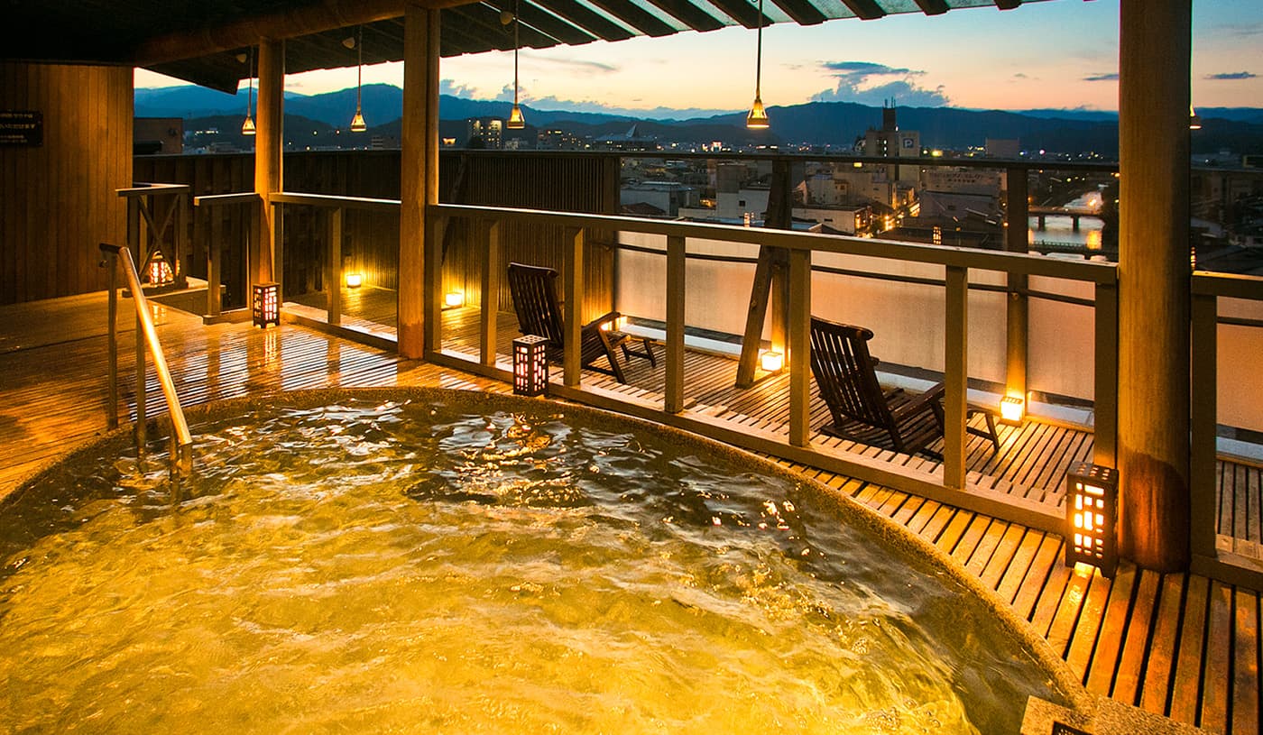 Rooftop open-air rotenburo at dusk overlooking the Takayama town and mountains at Honjin Hiranoya Kofukan