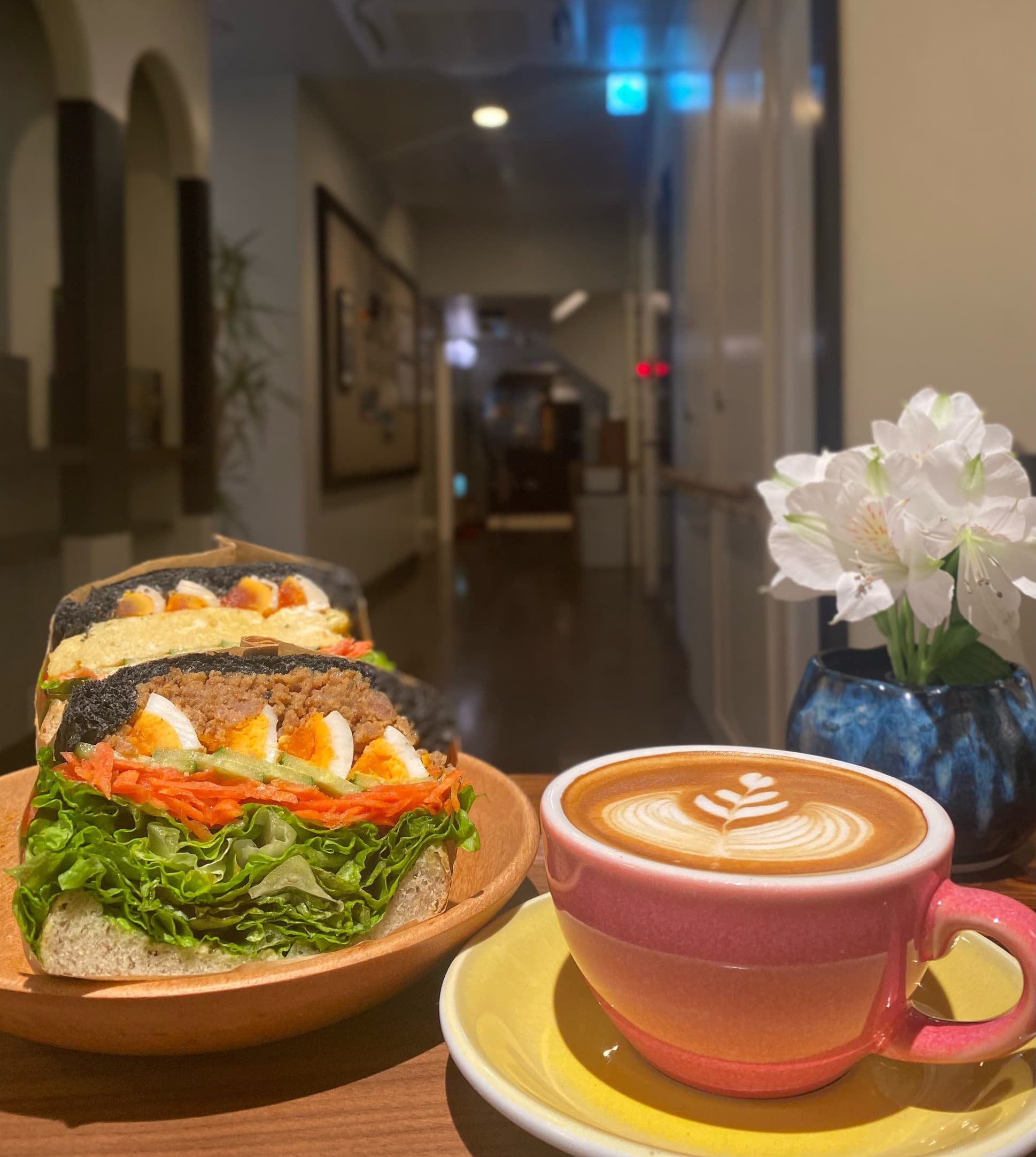 Sandwich and latte art coffee served at the cafe inside Kimi Ryokan with the hallway behind