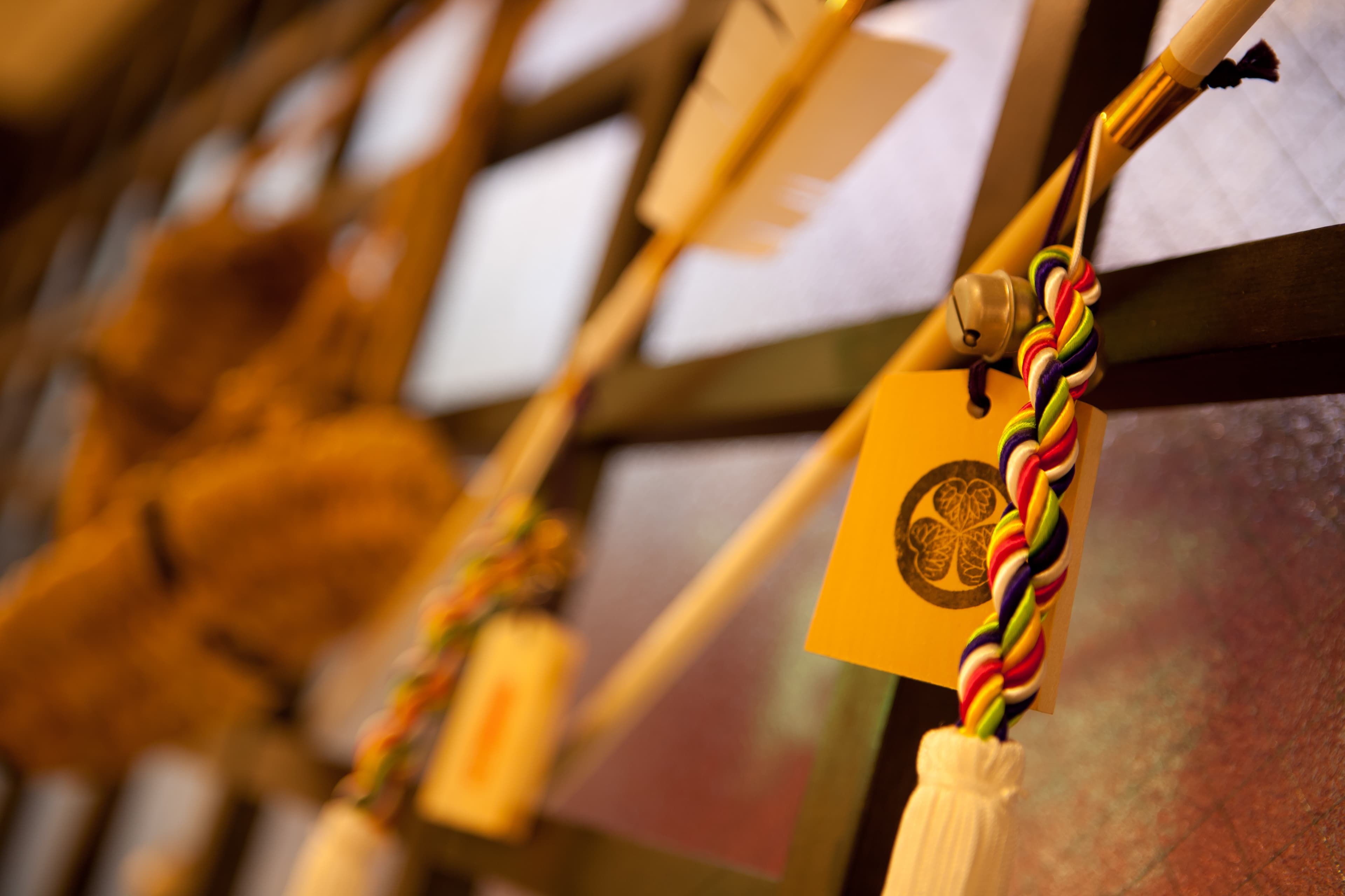 Close-up of colorful braided omamori charms with a family crest tag hanging at Kimi Ryokan Tokyo