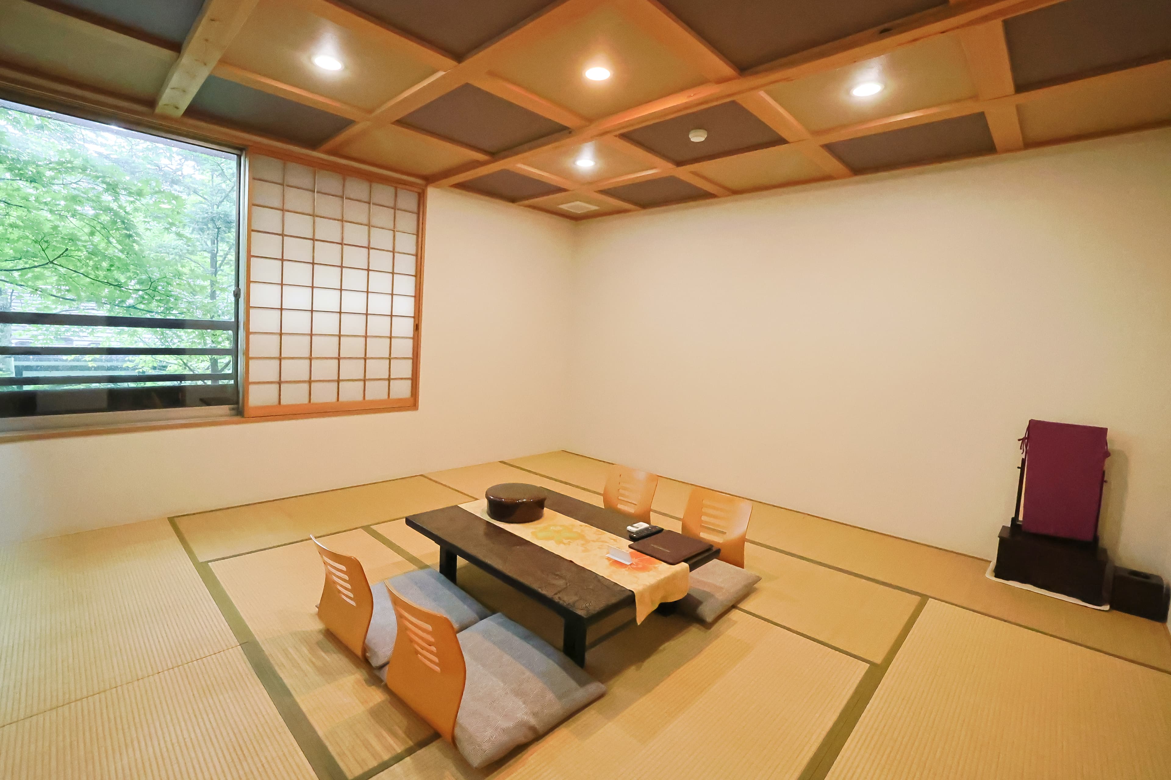 Spacious tatami guest room with a coffered ceiling, low table and a shoji-screened garden window