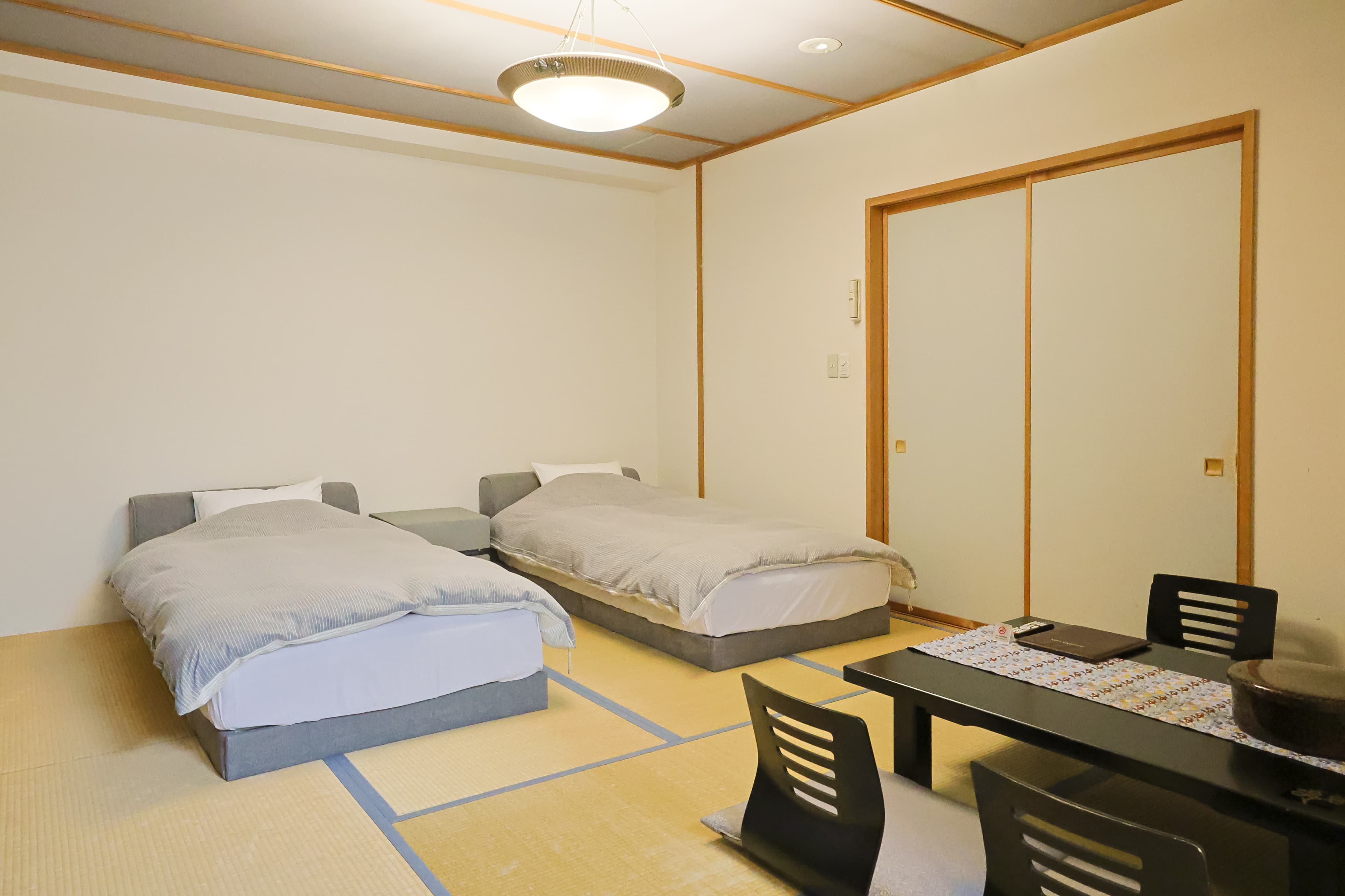 Tatami guest room with twin low beds and a black low table by a closet
