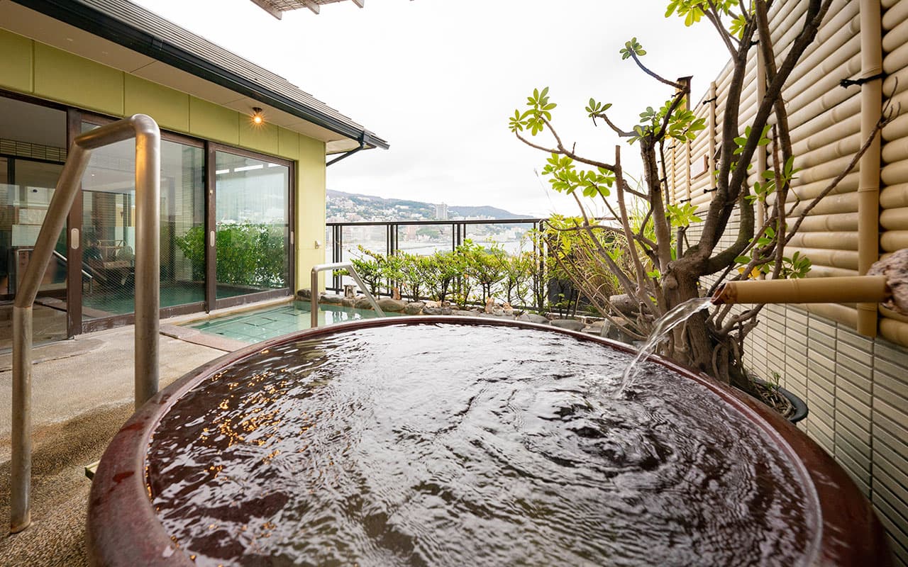 Outdoor ceramic kame jar bath with bamboo spout and bay view at Shukaen Yunohanazen in Atami