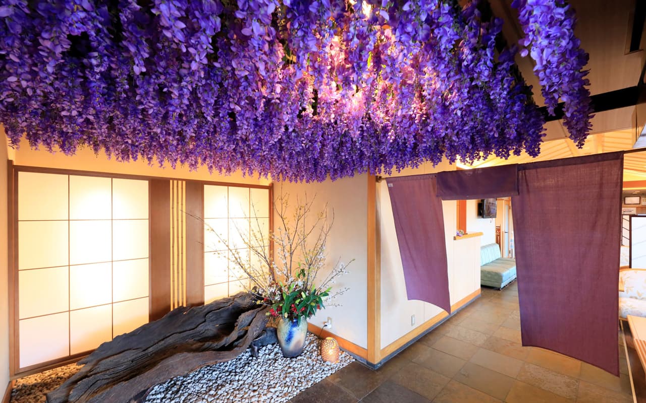 Entrance hall framed by cascading purple wisteria, shoji screens and an ikebana arrangement