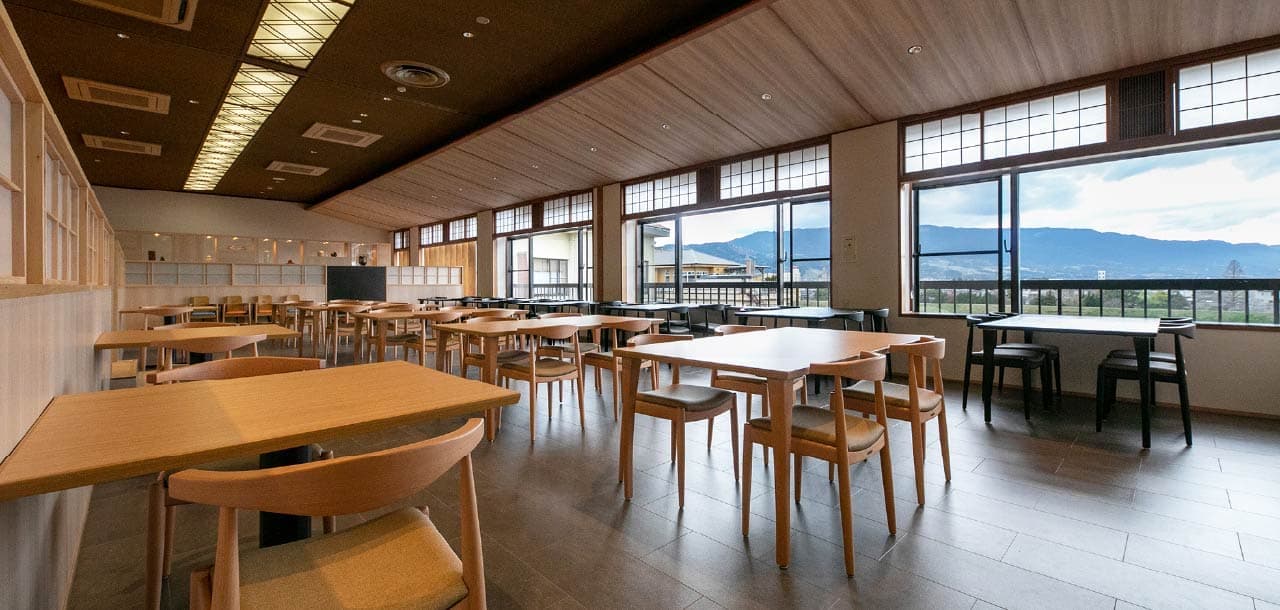 Bright dining hall at Taisenkaku with wooden tables and large windows overlooking the Chikugo River plain and mountains