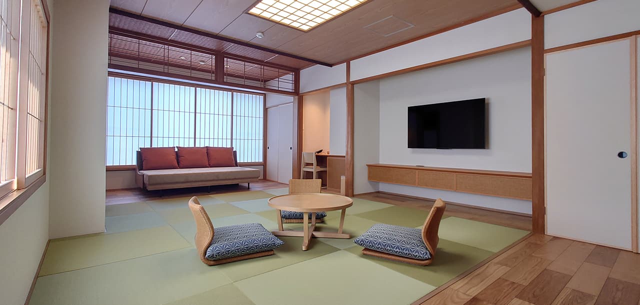 Japanese-modern guest room at Taisenkaku with low sofa, tatami area and hanging scroll alcove