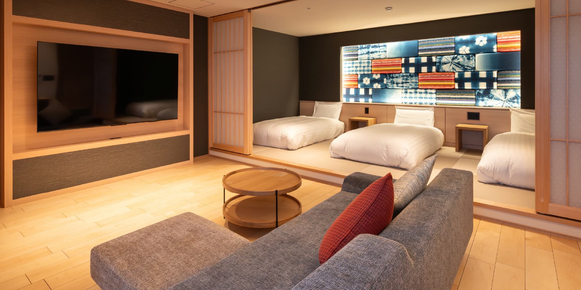 Renovated Japanese-modern guest room at Taisenkaku with three beds and indigo textile wall art