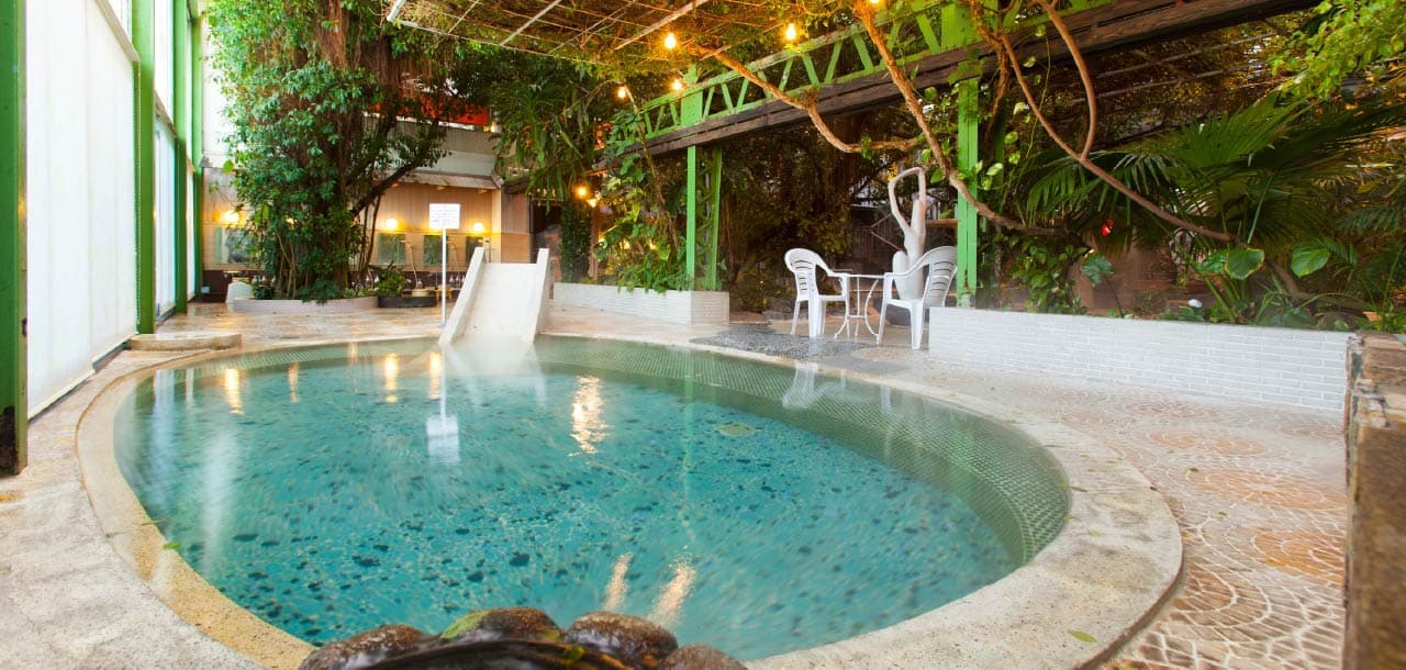 Taisenkaku signature jungle bath, a large indoor hot-spring pool under tropical greenery and string lights