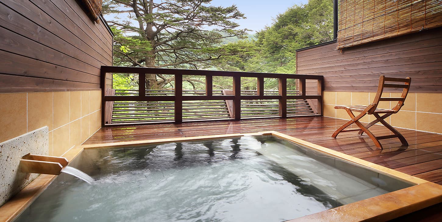 Open-air rotenburo bath at Hotel Tsuga no Ki on a wooden deck facing pines and the Kinugawa valley