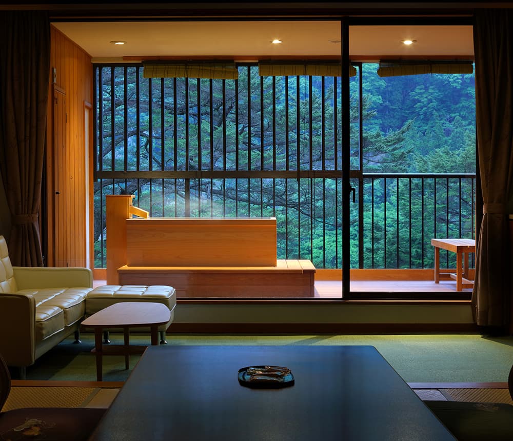Tatami guest room with a private wooden open-air bath by a wall of windows