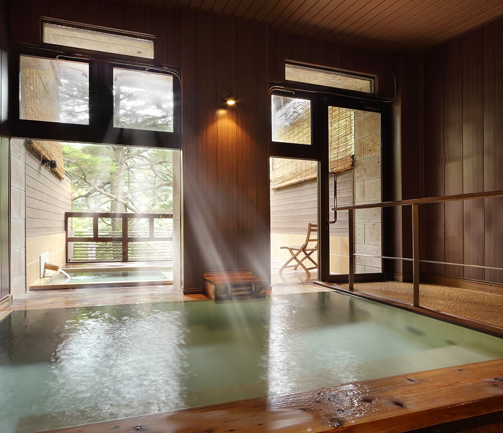Indoor cypress hot-spring bath with steam and forest views through the windows