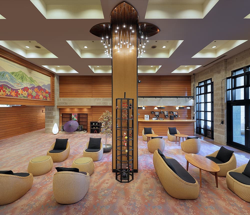 Lobby lounge with woven rattan chairs and a mountain foliage mural