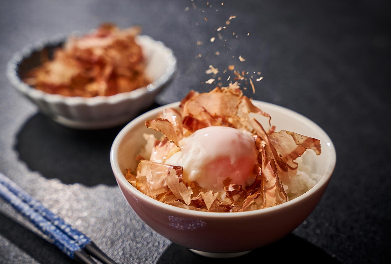 Rantei morning dish of freshly shaved katsuobushi over onsen-tamago in ceramic bowl — signature breakfast item at Akiu Onsen Rantei