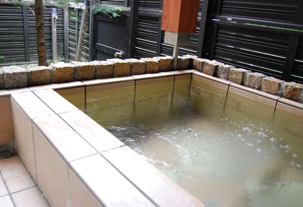 Tiled private open-air onsen bath beside greenery