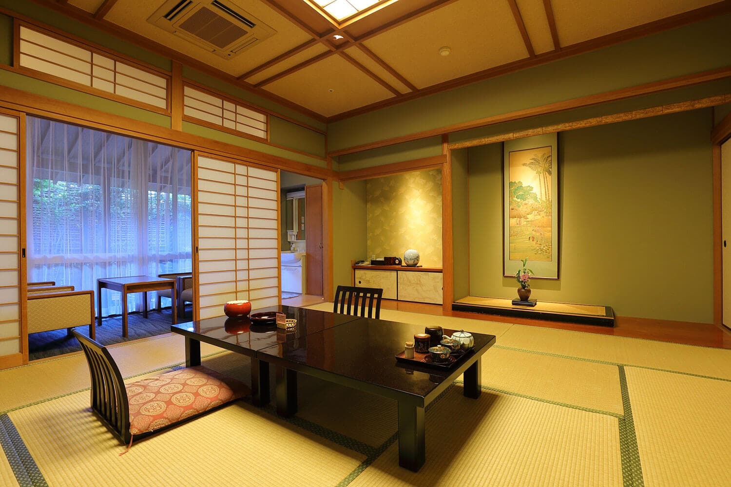 Traditional tatami guest room at Arima Gyoen with low lacquer table, tokonoma alcove and shoji opening to a garden veranda