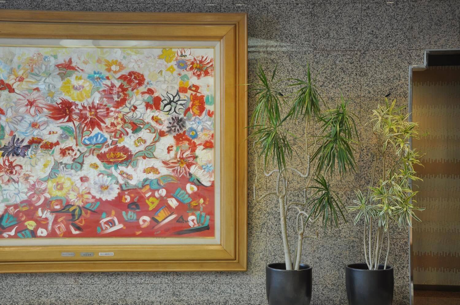 Arima Gyoen lobby corner with a large framed floral painting, stone wall and potted plants